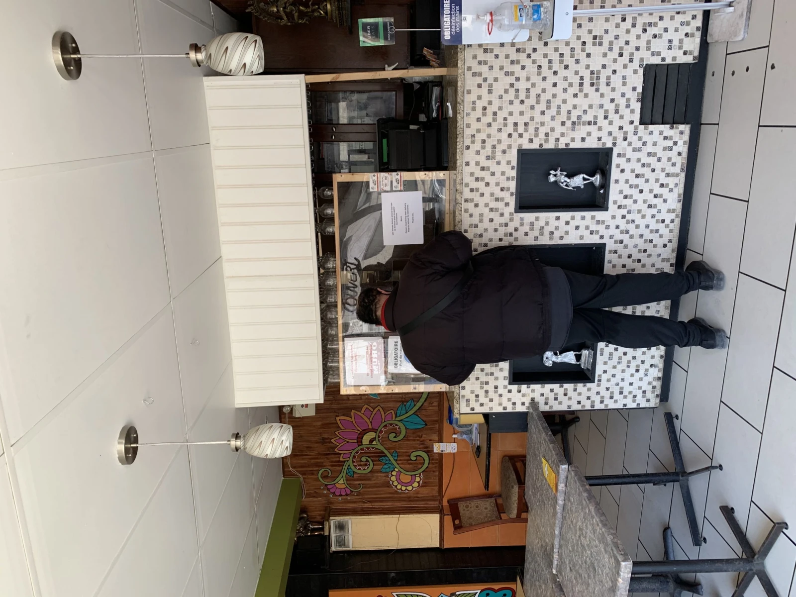 Bhumika qui sert un habitué derrière son écran de plastique.