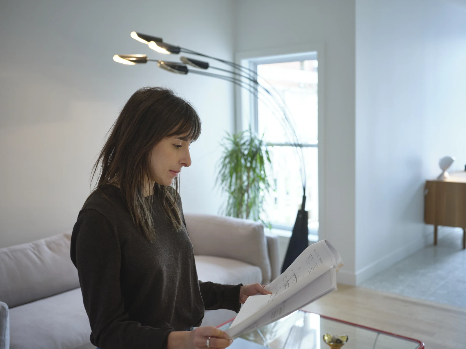 Pour l’espace salon, les designers ont opté pour un éclairage blanc neutre, obtenu à la fois par la lumière naturelle diffusée par les fenêtres et par la lampe sur pied vintage qui se trouve dans la pièce. Il est recommandé de privilégier des ampoules à DEL d’une température de couleur blanc chaud variant entre 2 200 et 3 000 kelvins.