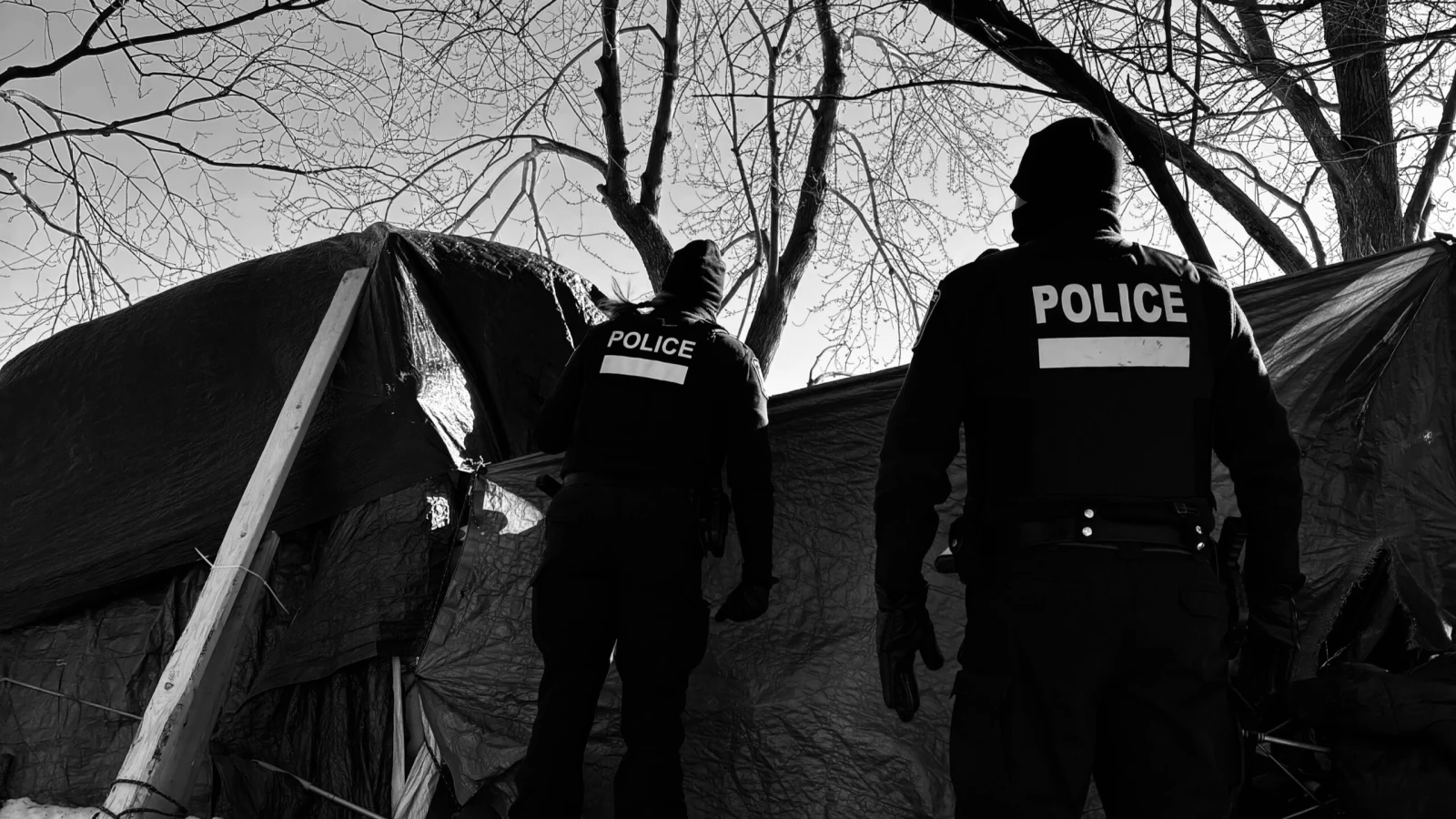 Deux policiers font le tour des tentes dans un campement de la rue Notre-Dame.